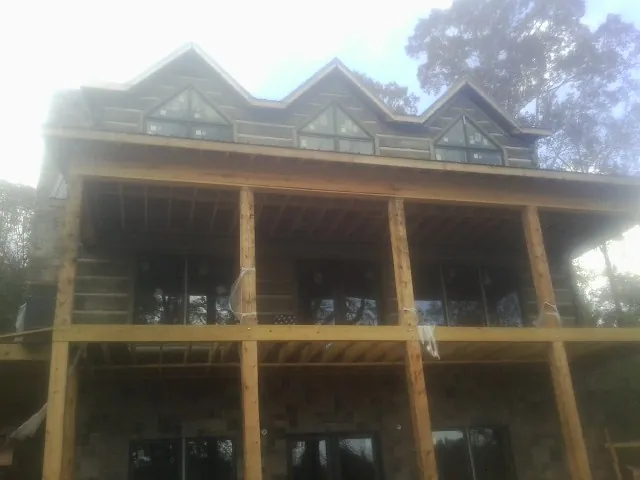 Dormers and porch framing on a large log home under construction — Roof Coating work by our crew in Mascot