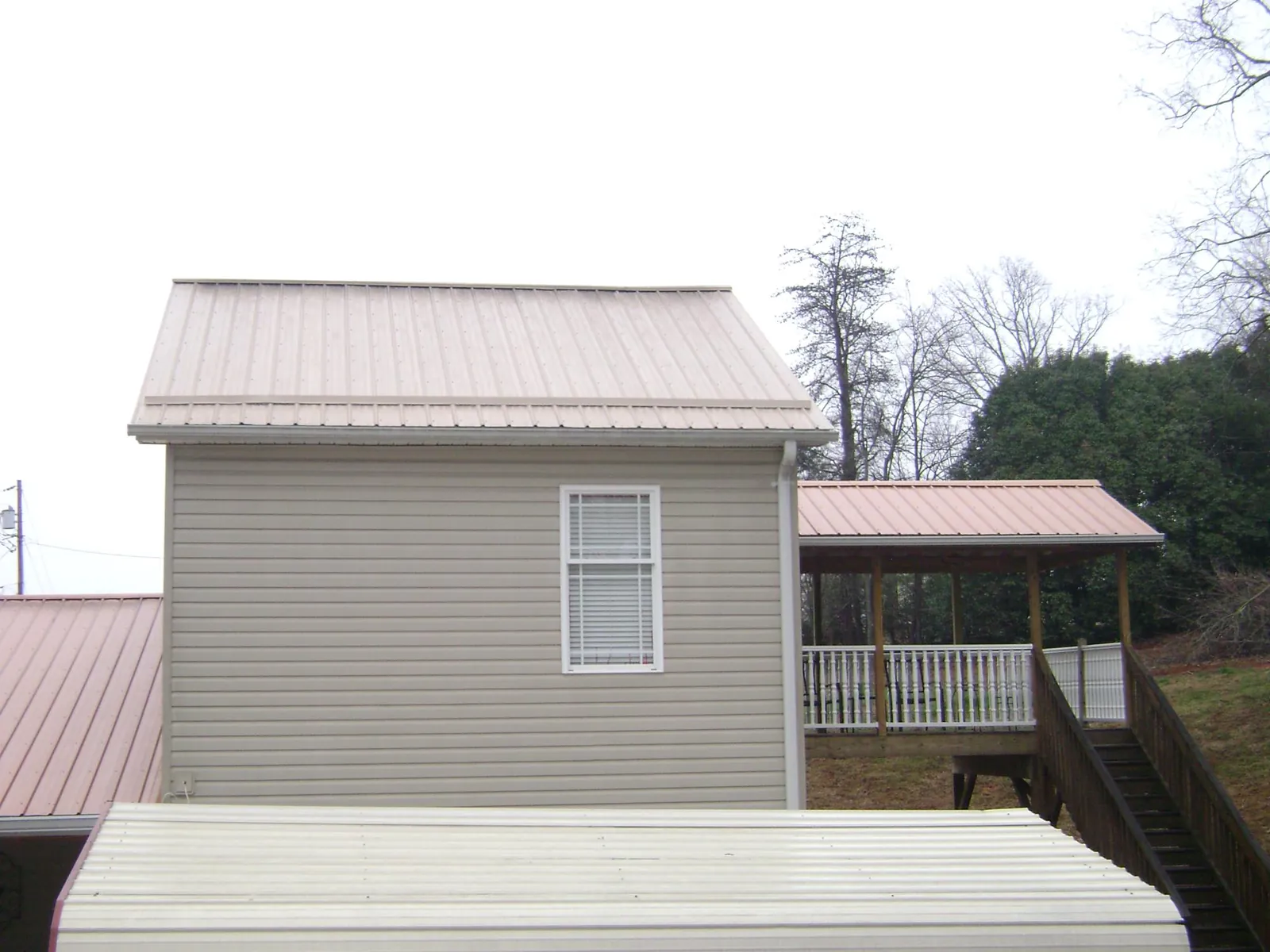 Tan metal roofs on a two story addition and attached porch, from a Roof Replacement job in Mascot