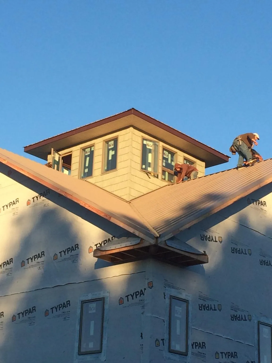 Roofers working around a rooftop cupola on a new metal roof at sunset — Roof Waterproofing in Mascot by Roofing Brothers